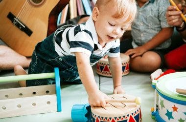 Little kid playing with a wooden drum set